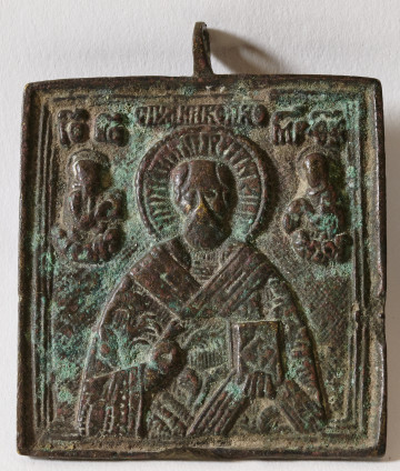 ikona z frontalnym wizerunkiem św. Mikołaja w półpostaci, błogosławiącego prawicą, w lewej ręce trzymającego zamkniętą księgę Ewangelii, odzianego w szaty biskupie; przy głowie Świętego obustronnie półpostacie Chrystusa i Bogurodzicy; inskrypcje cyrylickie 